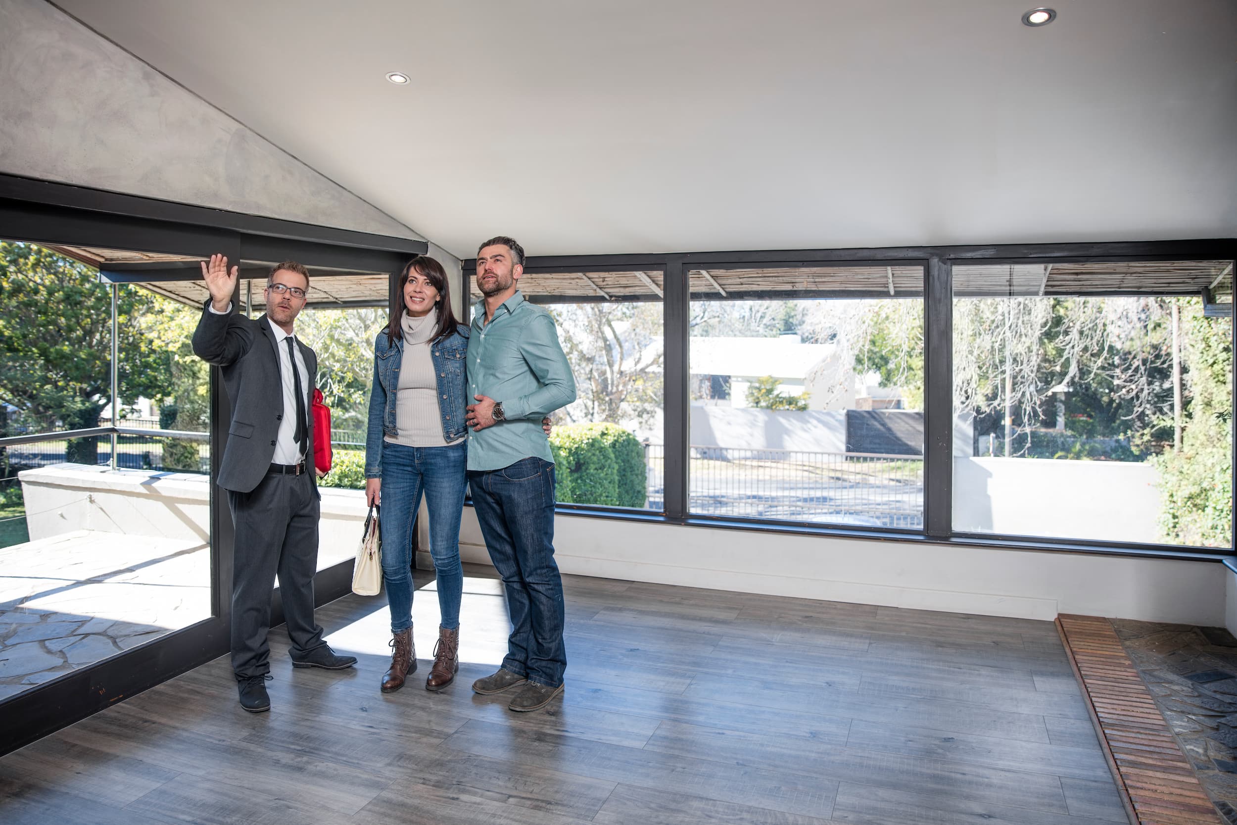 Real estate agent showing modern home to couple during property inspection in daylight