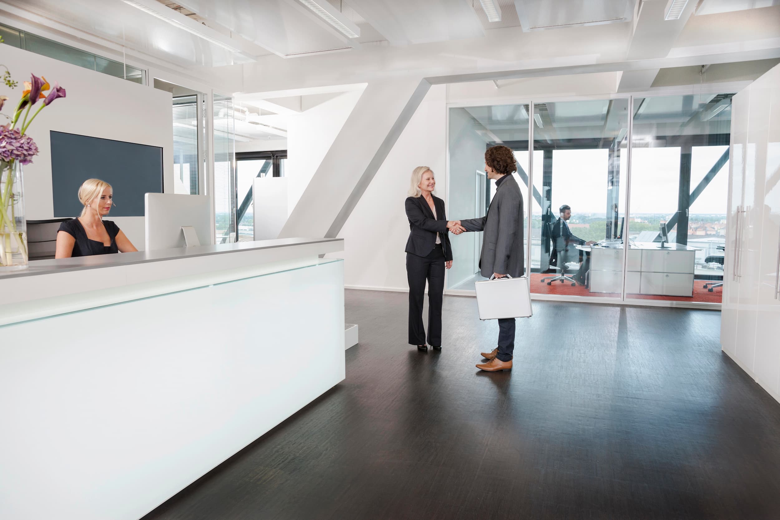 Businesswoman greeting client in modern office lobby